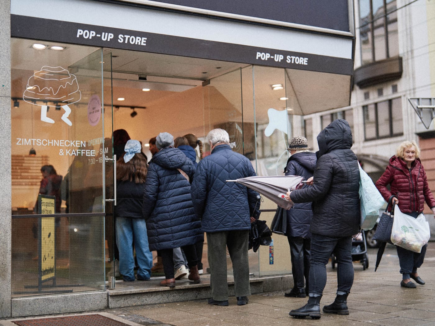 Eine Menschenschlange vor einem Zimtwirbel Pop-Up Store, Window Display im Corporate Design