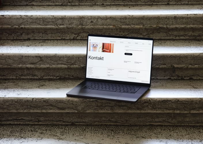 Geöffneter Laptop steht auf Stufen und zeigt gestaltete Webstite von Angyan Legal.