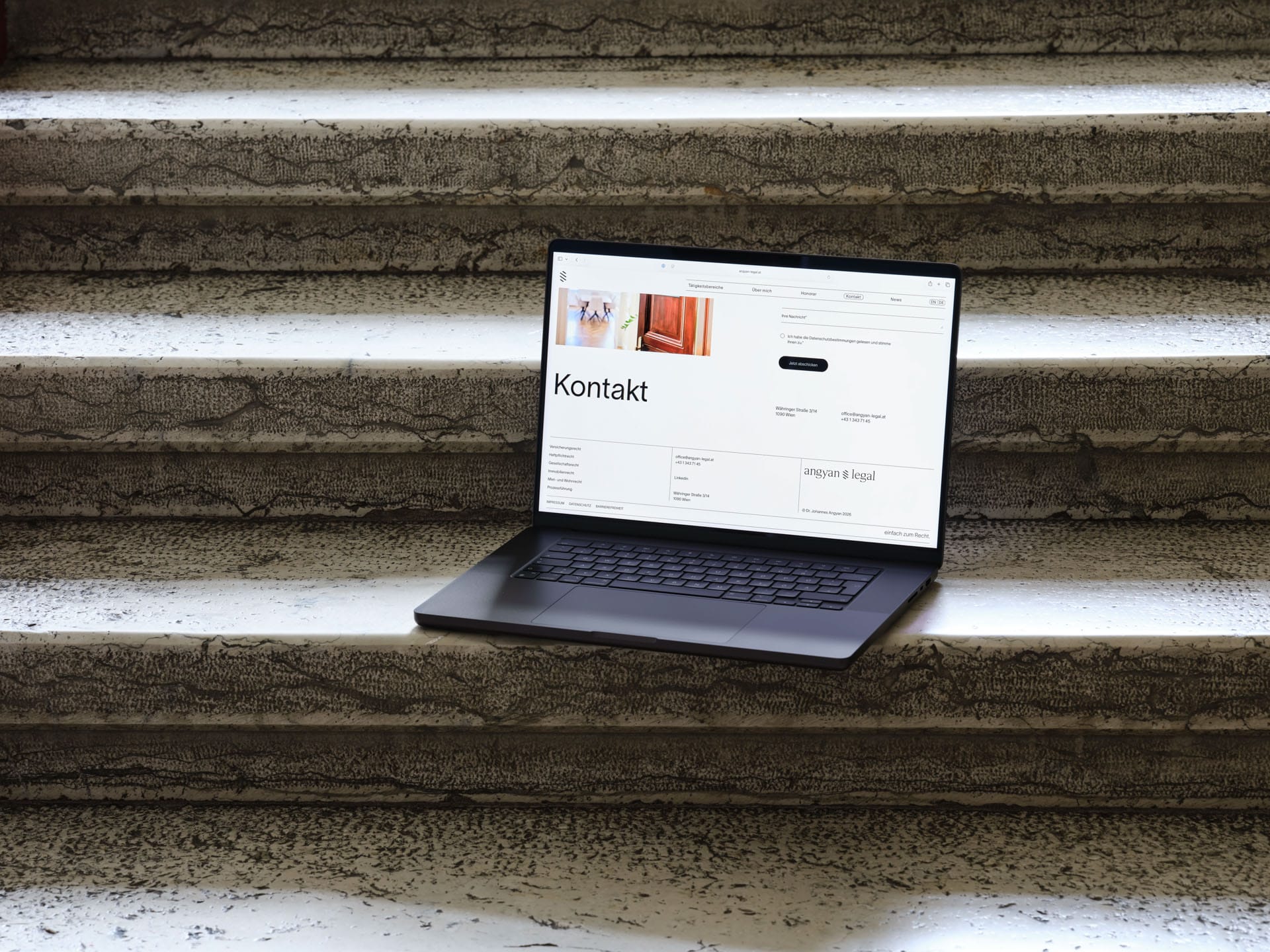 Geöffneter Laptop steht auf Stufen und zeigt gestaltete Webstite von Angyan Legal.